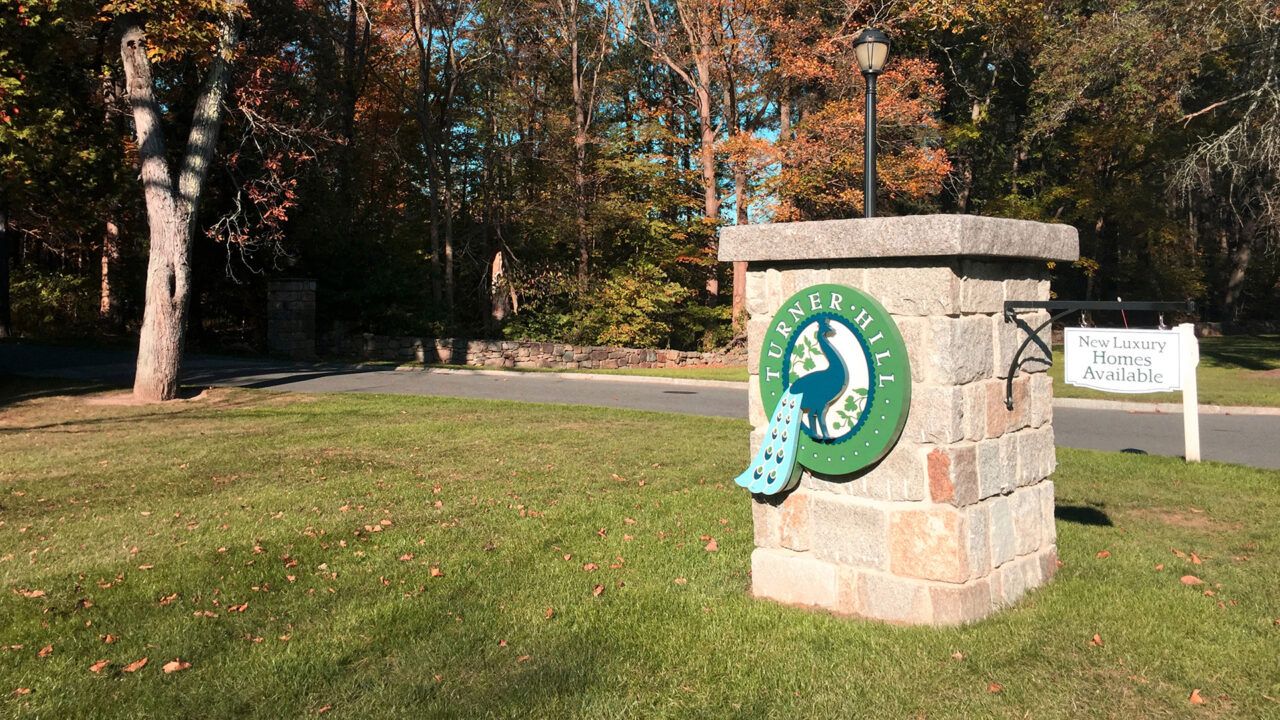 Turner Hill stone sign with peacock logo in the fall
