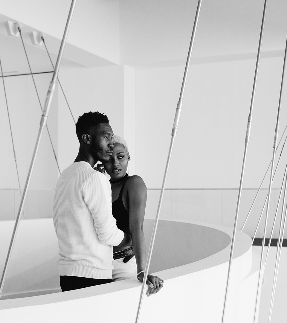 Black serious couple embracing in a white balcony