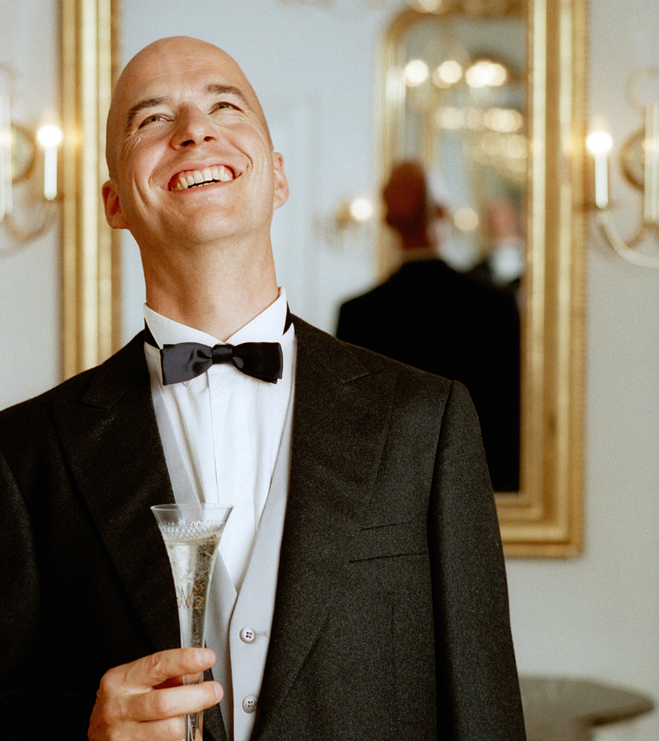 the sudbury bald man smiling and holding champagne glass