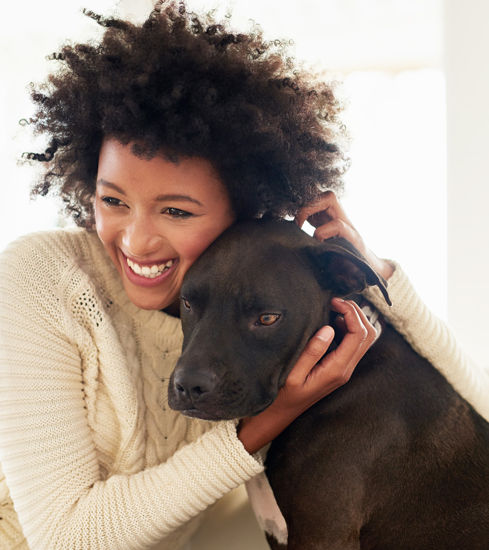 Boston East woman hugging black lab dog