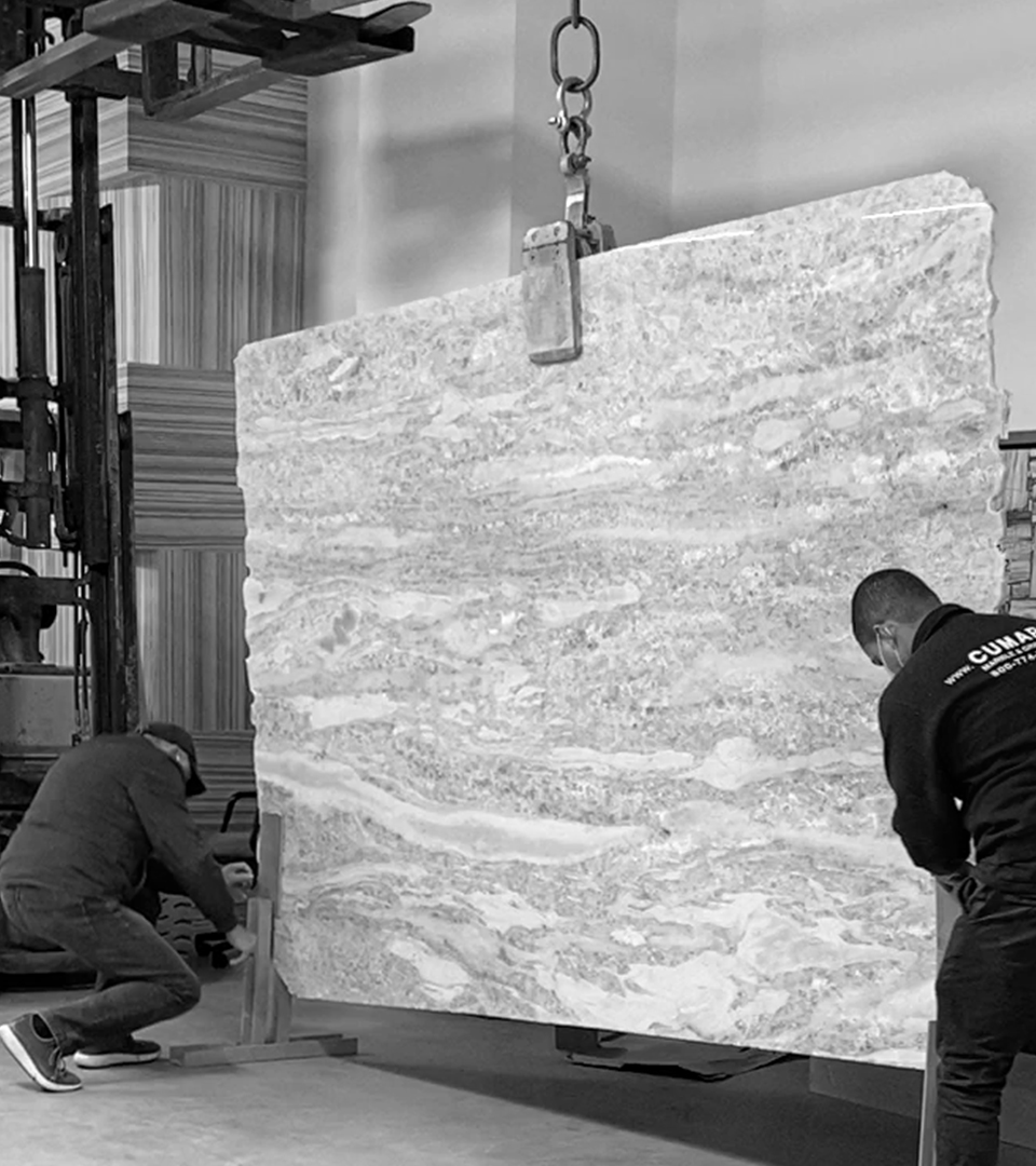 two men moving a slab of stone with forklift