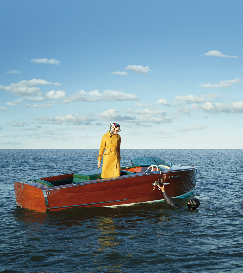 echelonseaport woman in yellow coat in red boat with diver holding champagne by adams design real estate, corporate, retail, hospitality