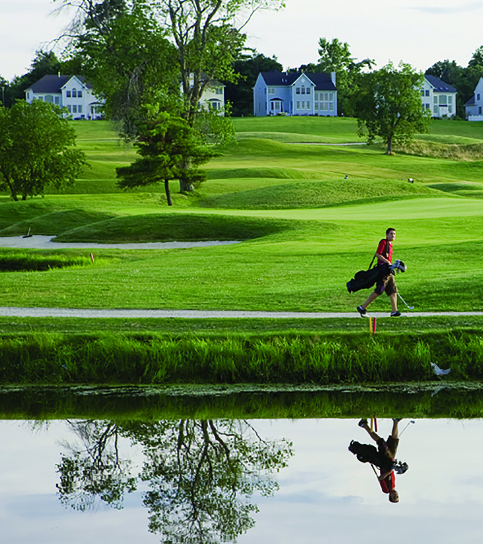 merrimack valley golf club man walking with clubs with reflection in pond