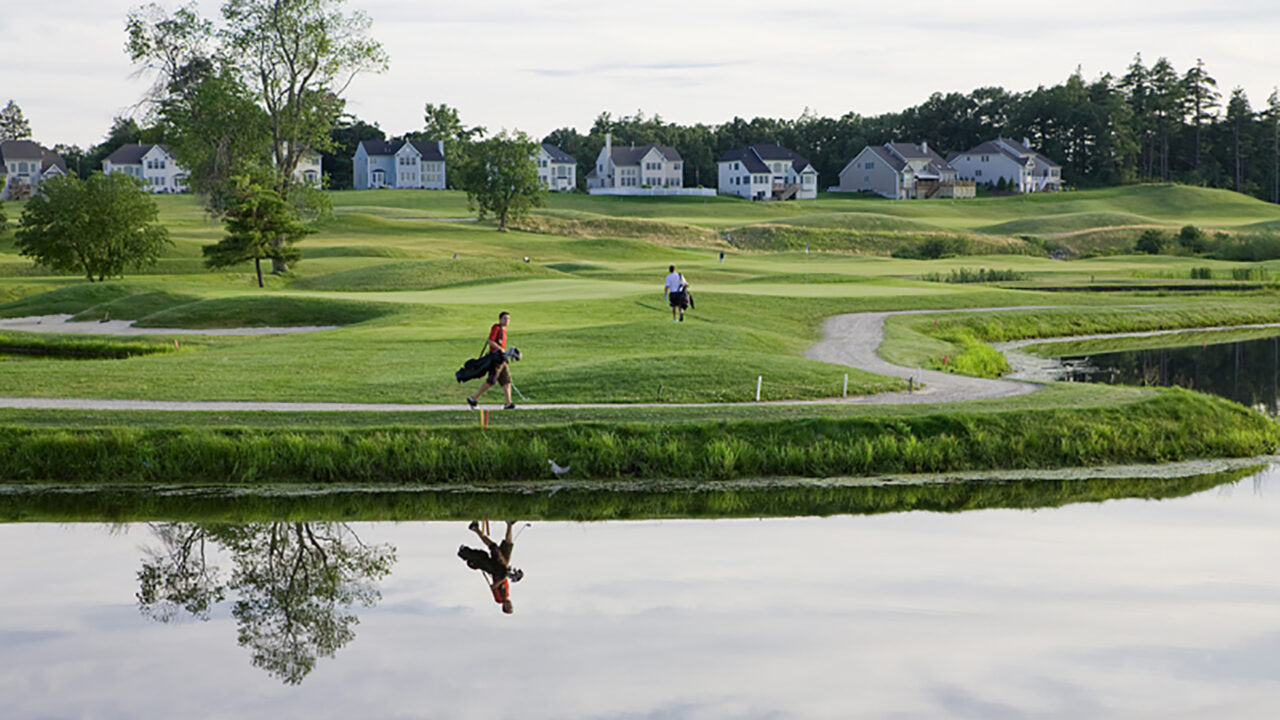 merrimack valley golf club man walking with culbs with houses in background jpg
