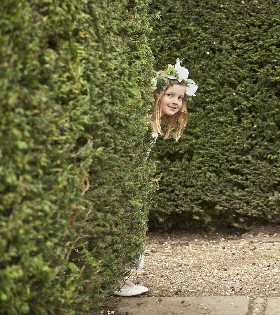 seaport hotel flower girl peeking from behind hedge.jpg