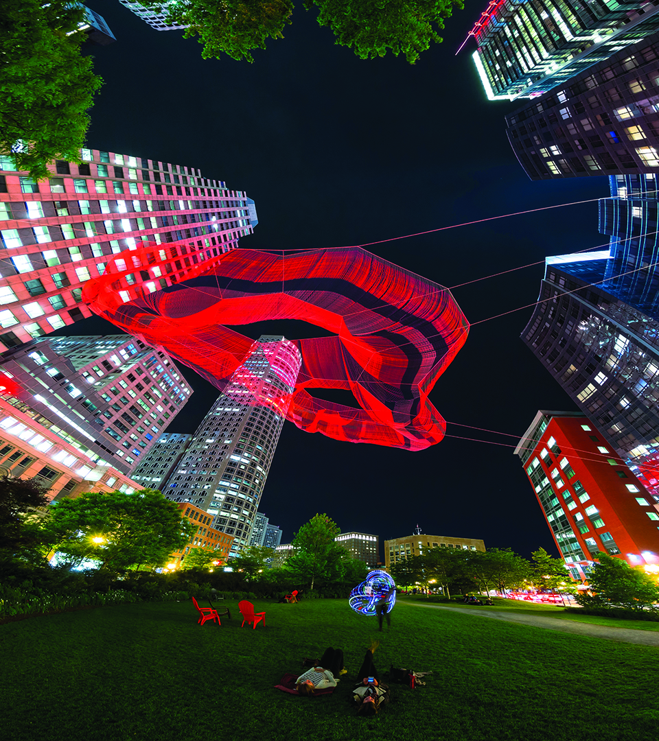 sudbury night view of boston's Rose Fitzgerald Kennedy Greenway with a giant rope sculpture by artist Janet Echelman, suspended over the park. Over 270 feet in length at its longest point, it contains 100 miles of rope.