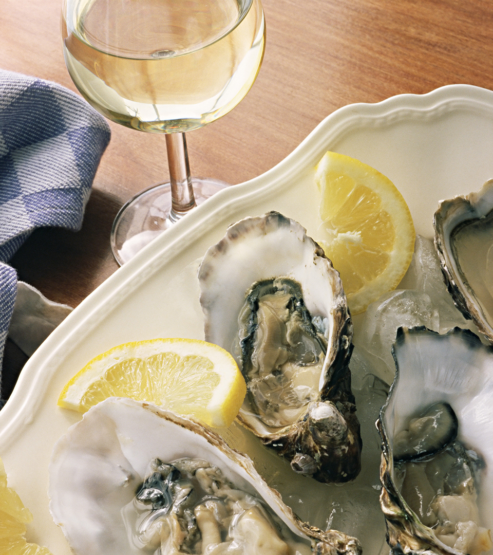 top view of glass of white wine and plate of oysters