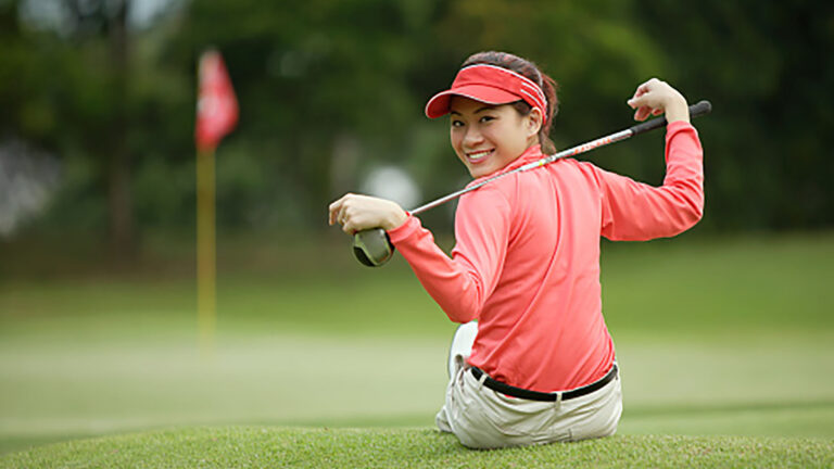 cape club young asian woman holding golf club sitting on golf course looking at camera