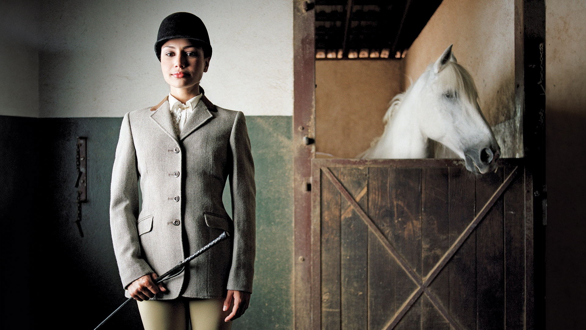 shreve crump and low equestrian woman standing next to white horse in stable