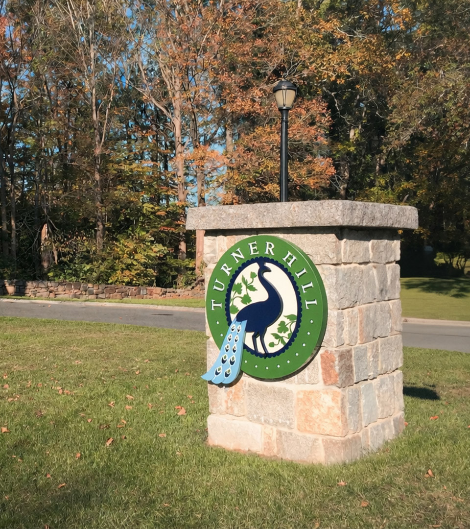 Turner Hill stone entry monument featuring the peacock logo at the entrance to the historic estate.
